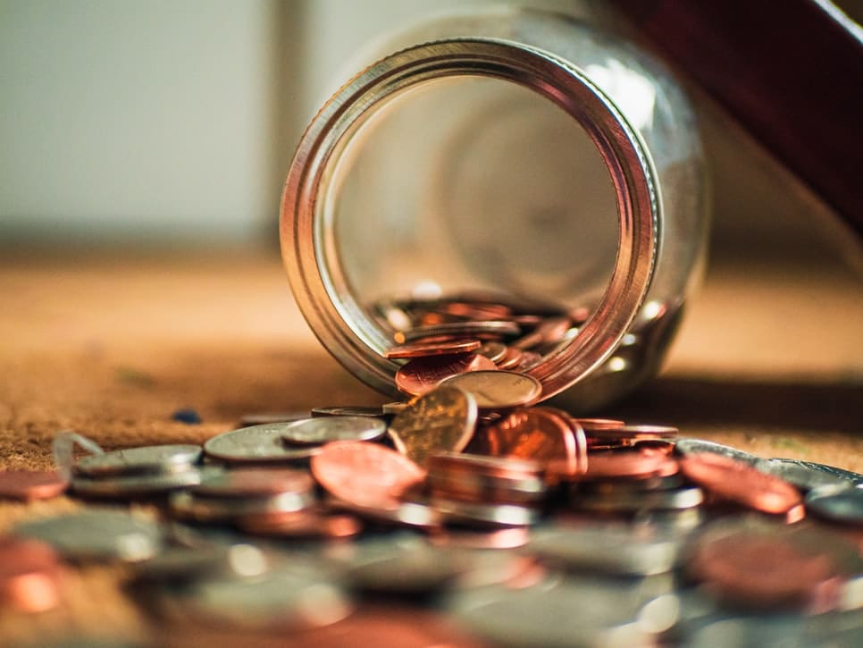 A pile of coins spilling out of a jar.