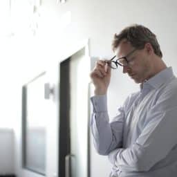 Younger man looking stressed and resting against a wall.