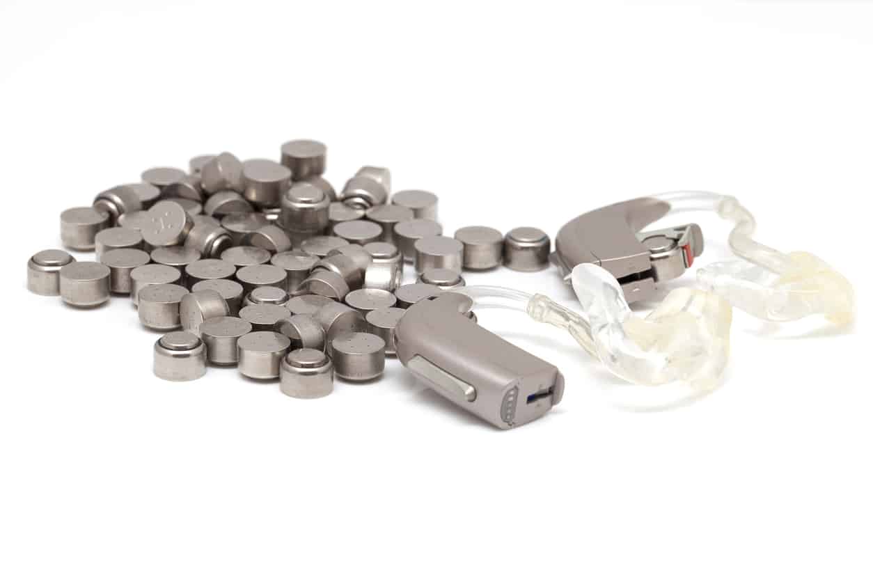 Hearing aids sitting next to a pile of batteries.