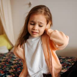 Young girl holds ear in pain