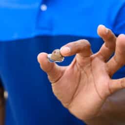 Close up of a person holding an ITE hearing aid
