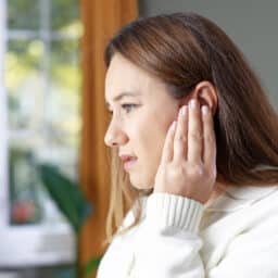 Woman with tinnitus holding her ears