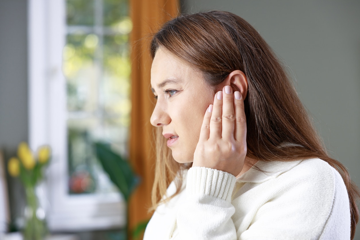 Woman with tinnitus holding her ears.