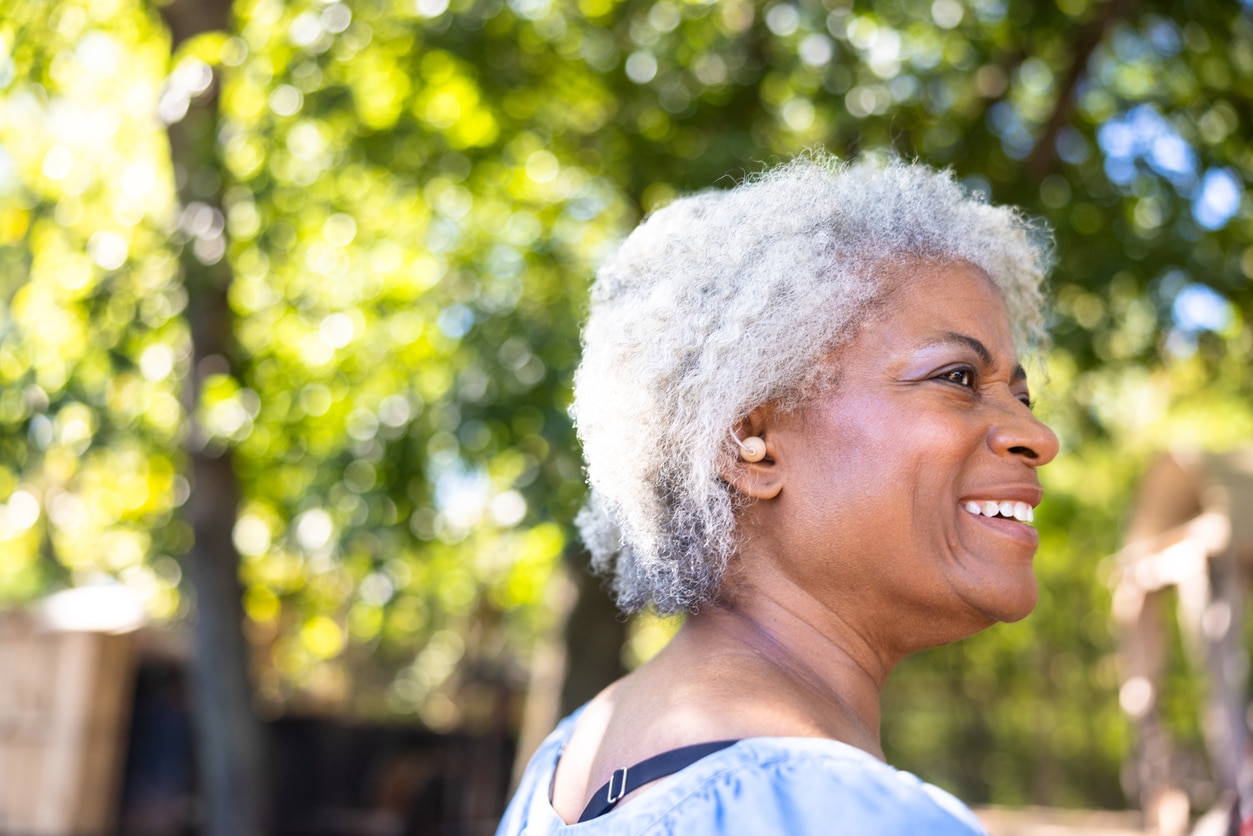 Senior woman smiling, showing off her hearing aid.